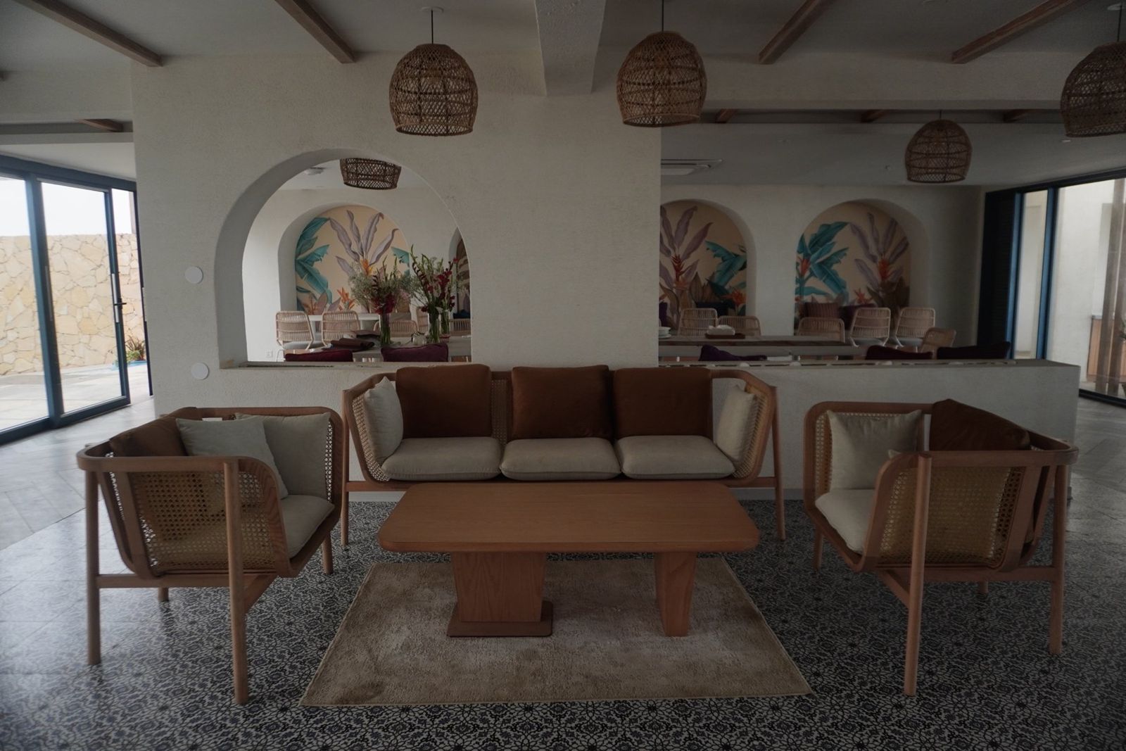 Café lounge with rattan furniture, patterned tiles and arched murals